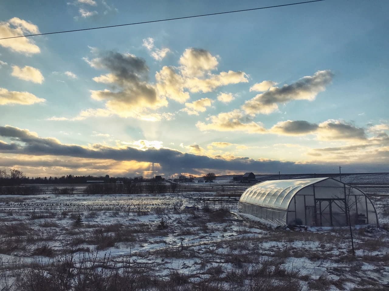 A Greenhouse Standing in an Icy Windswept Field, in front of a glorious sunset